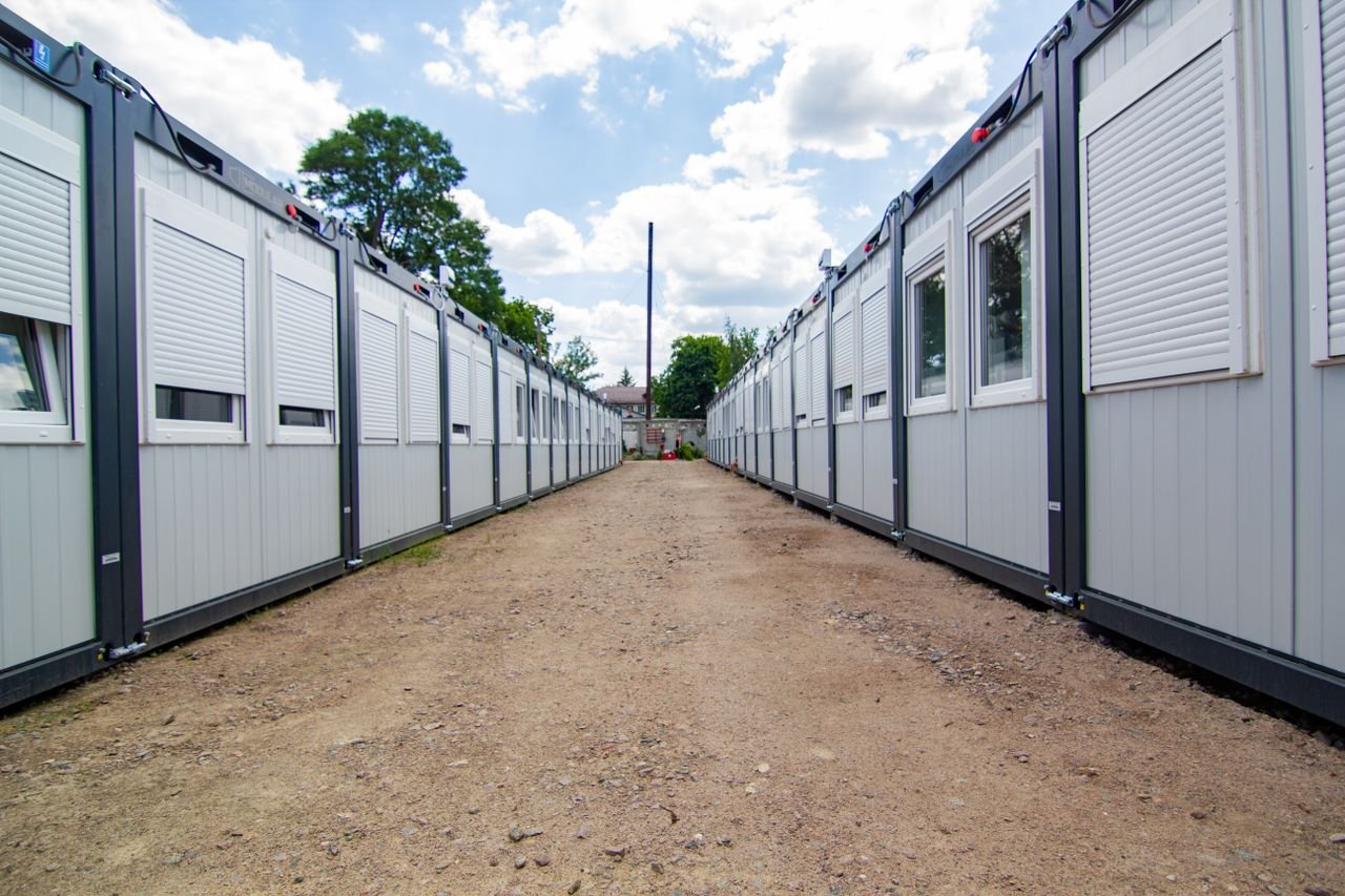 Services A clear sky view of two rows of temporary office buildings with a dirt pathway in between.
